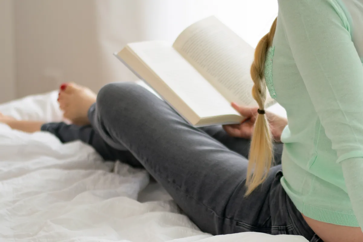 Woman reading a book in bed at home in Boynton Beach, Florida