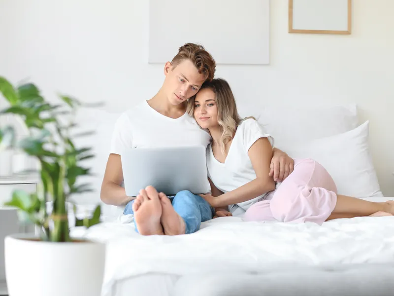 Couple sharing a laptop on a bed at home in Boynton Beach with online psychiatric care