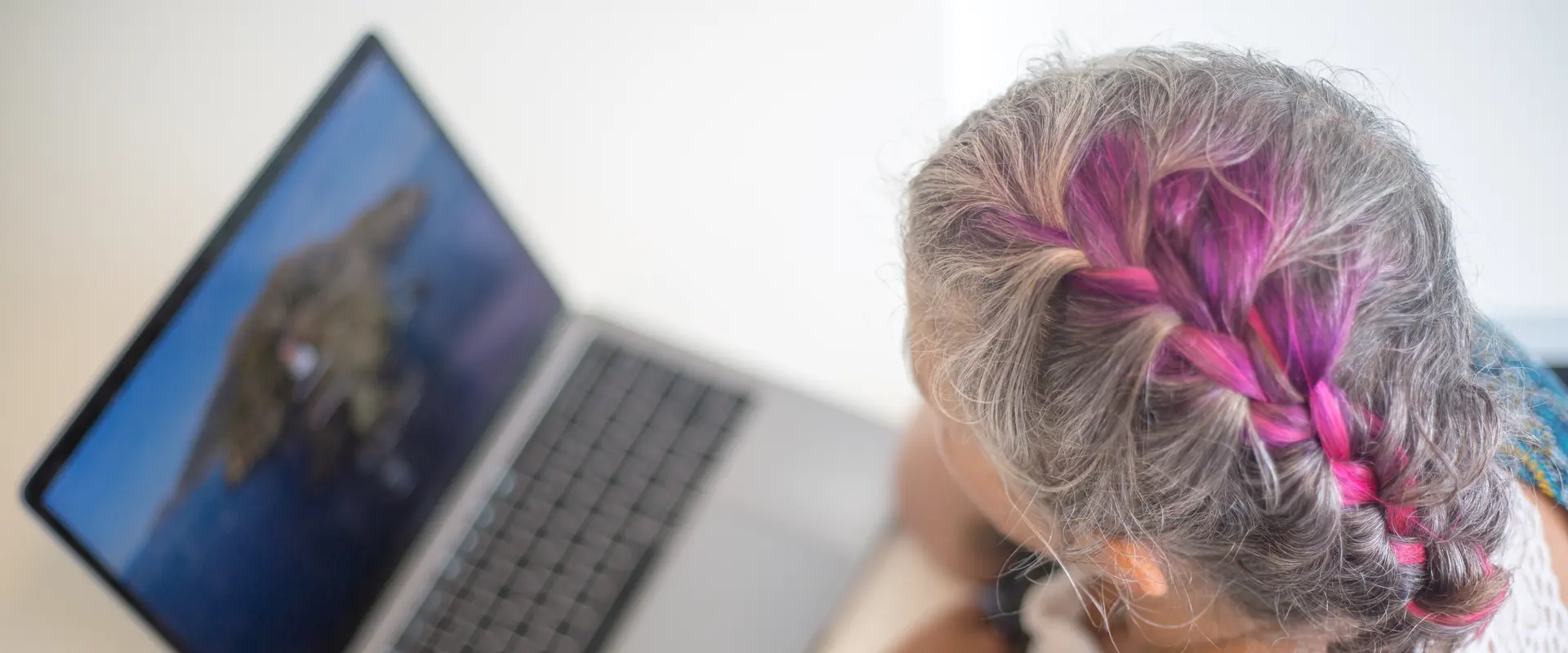 Older woman with braided hair using a laptop, joining a virtual psychiatrist visit from home in Boynton Beach, FL